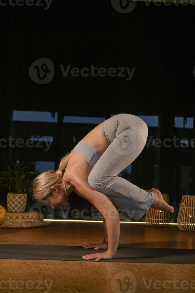Dynamic yoga practice showcasing a woman performing an advanced pose in a serene and well-lit indoor studio environment during a peaceful evening session photo