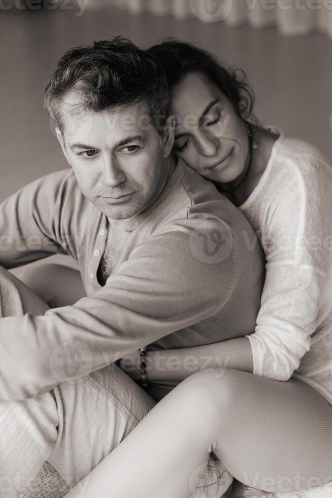 Couple engaging in mindfulness meditation practice while seated back to back in a serene indoor space during the late afternoon light... photo