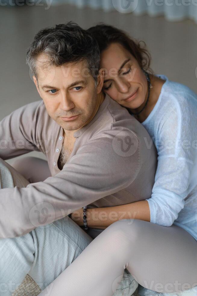 Couple engaging in mindfulness meditation practice while seated back to back in a serene indoor space during the late afternoon light photo