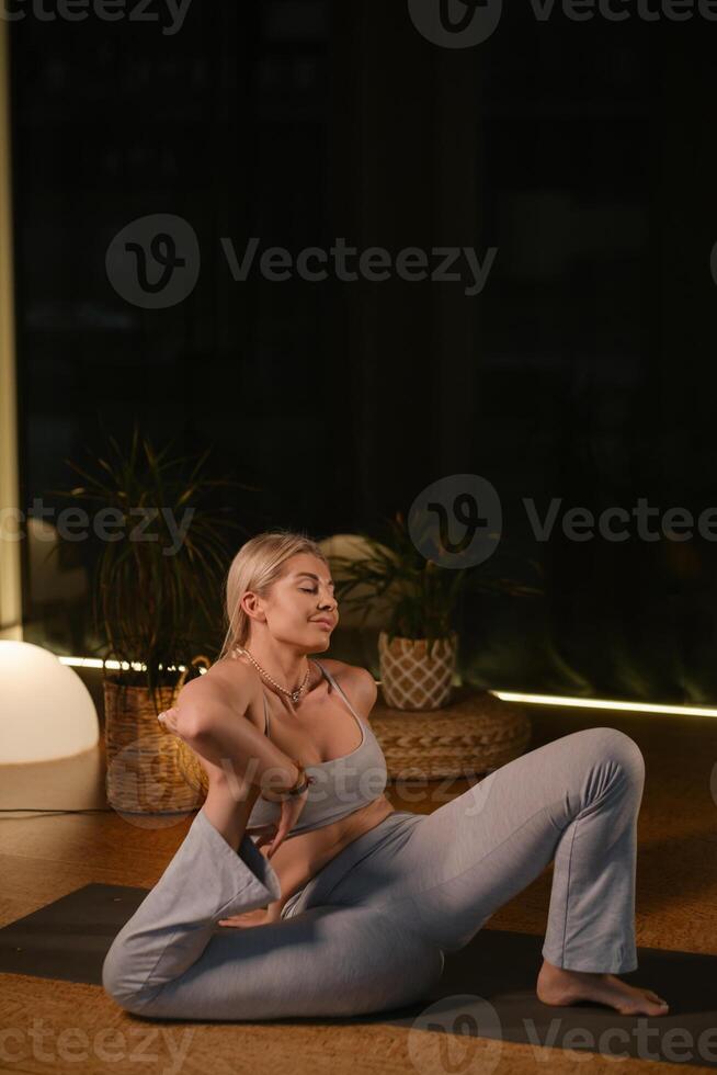 Practicing yoga in a serene indoor space with soft lighting and plants during the evening hours photo