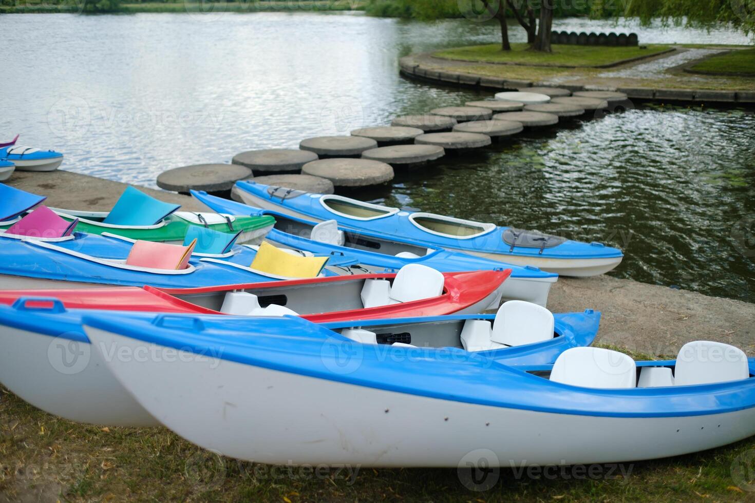 Colorful kayaks lined up by a serene lake on a sunny afternoon, ready for paddling adventures in nature photo