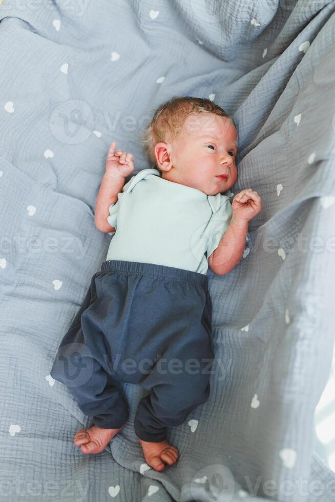 A charming and delightful newborn is peacefully resting on a soft, cozy blanket adorned with lovely heart patterns, dressed adorably, showcasing sweet and innocent expressions in warm, natural light photo