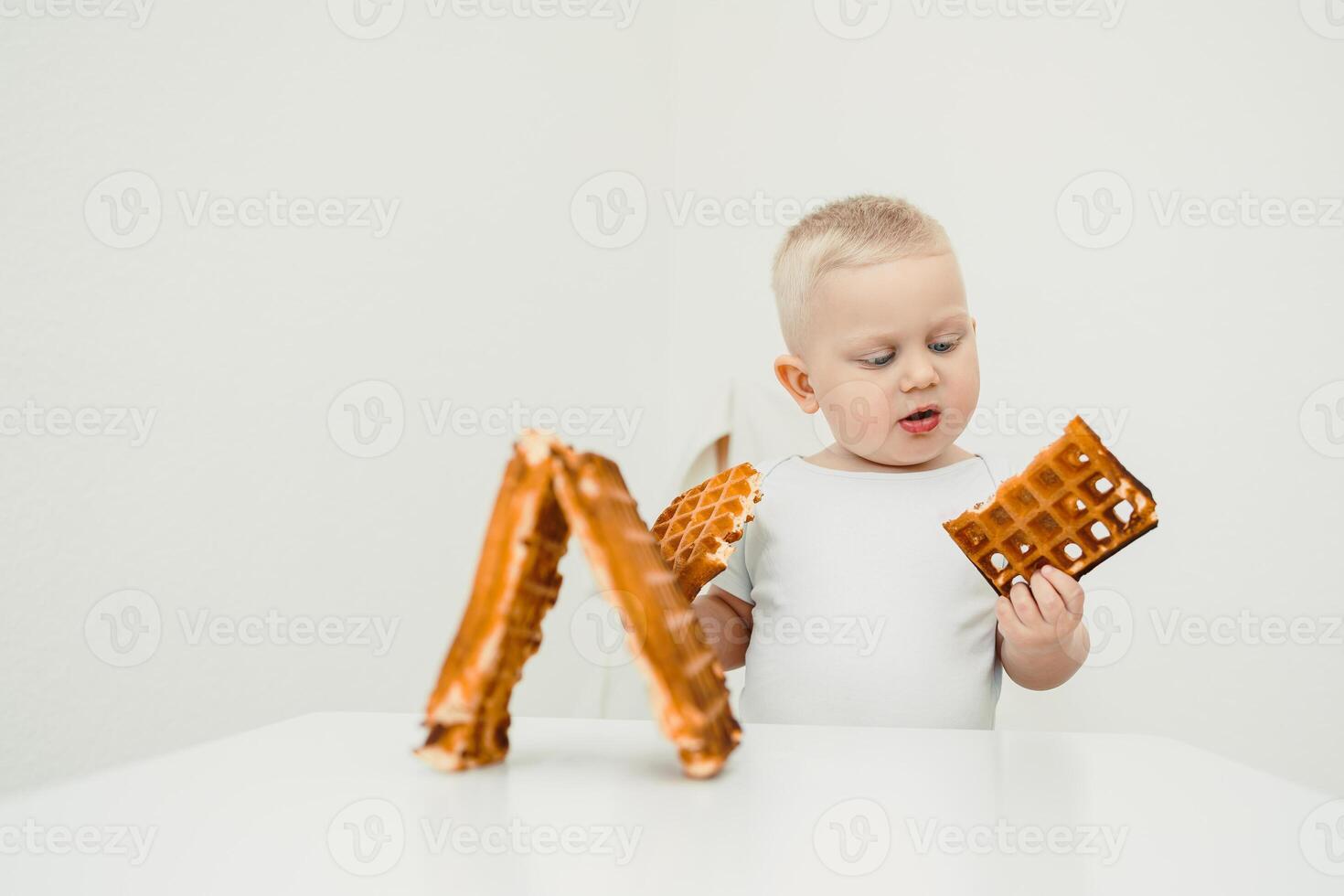 In a bright, minimalistic setting, a curious toddler joyfully explores delightful waffle shapes, showcasing their enthusiasm and excitement during this whimsical culinary adventure photo