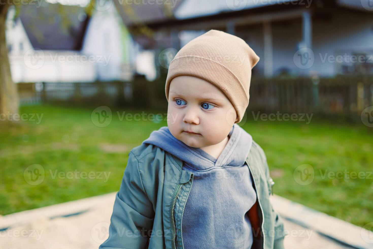 An adorable toddler enjoying the outdoor playground setting, showcasing bright blue eyes and wearing a stylish hat, epitomizing the essence of childhood innocence and playful curiosity photo