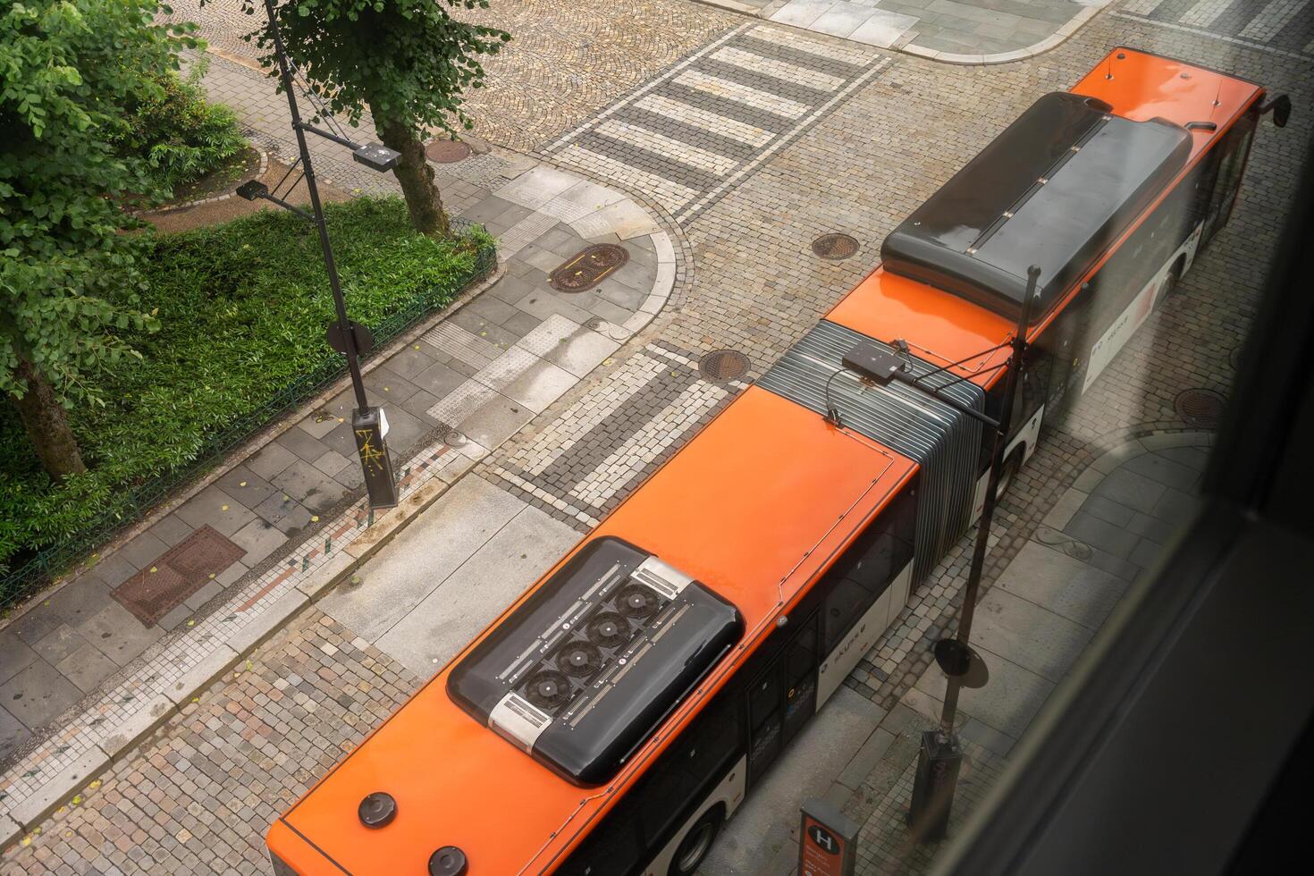 Bergen, Norway - July 7, 2024. Articulated city bus passing on cobblestone street seen from above photo