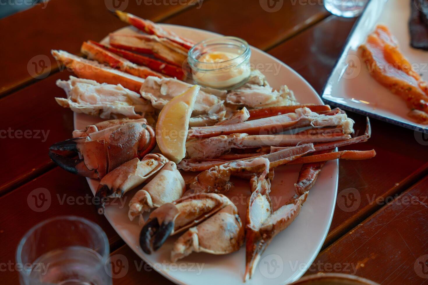 Fresh crab claws and king crab legs with lemon and sauce on white plate at seafood restaurant photo