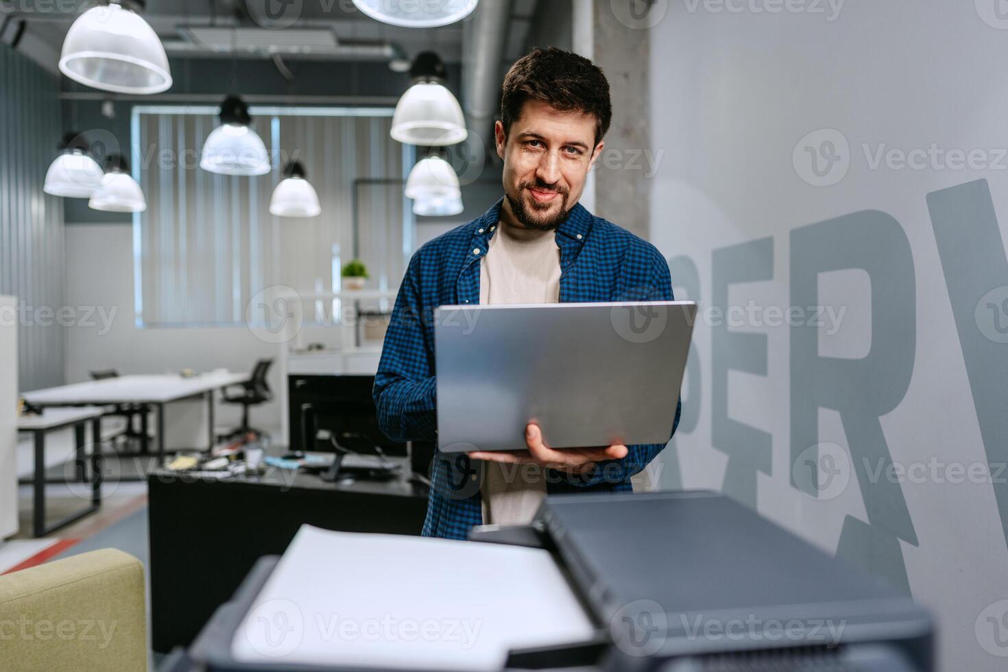 Man working on laptop in a modern office environment during daytime photo