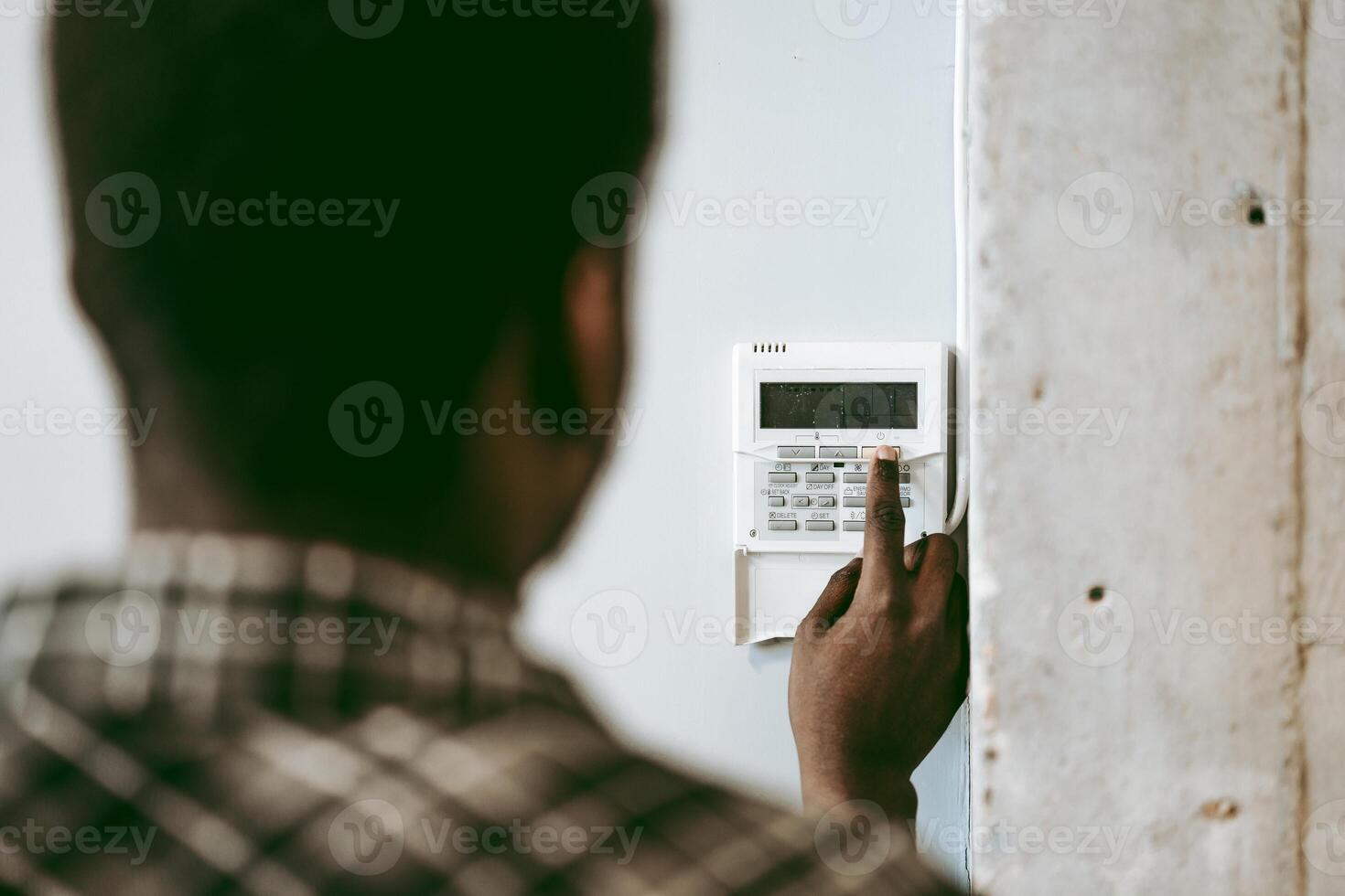 Man setting security system at home in the afternoon, focusing on keypad and monitoring device for safety photo