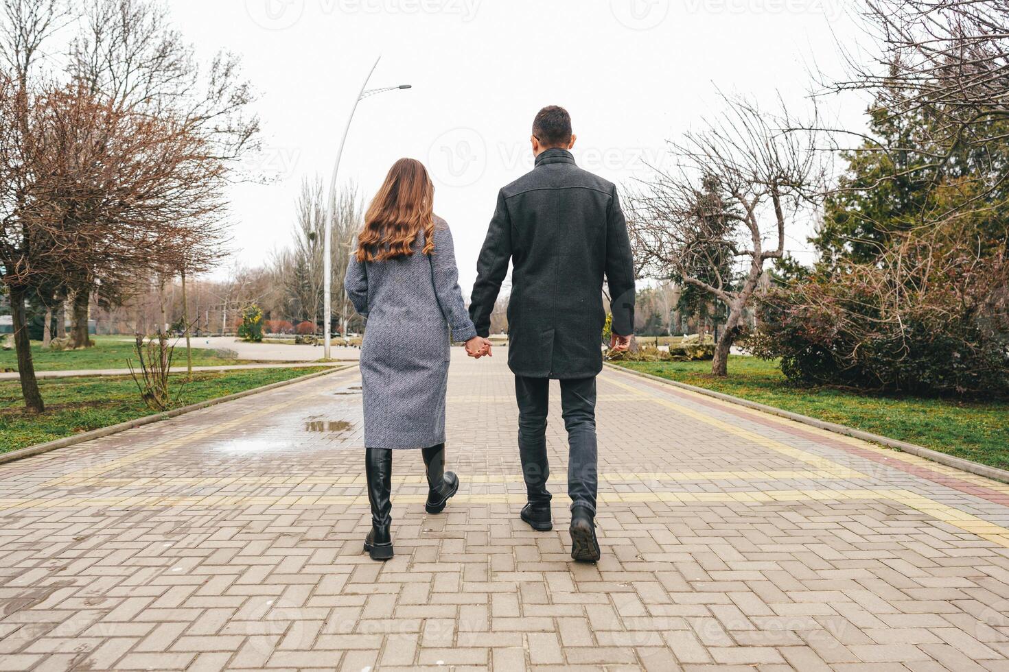 Couple walking hand in hand through a park on a cloudy day in autumn photo