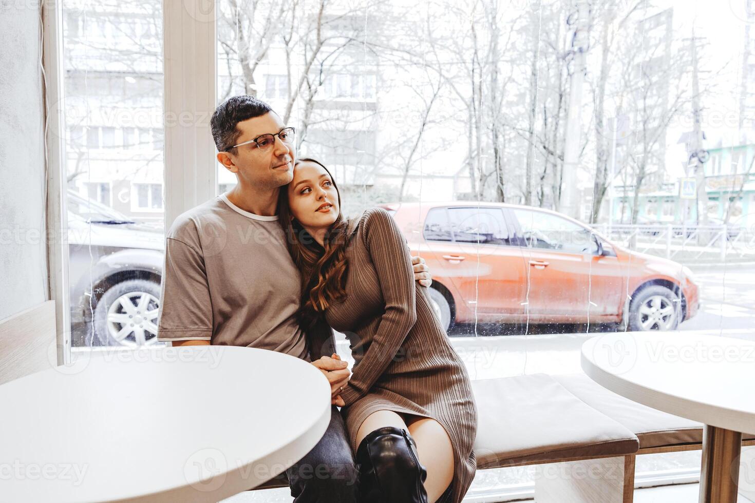 Couple enjoying a cozy moment together in a cafe during a snowy day while sipping warm drinks photo