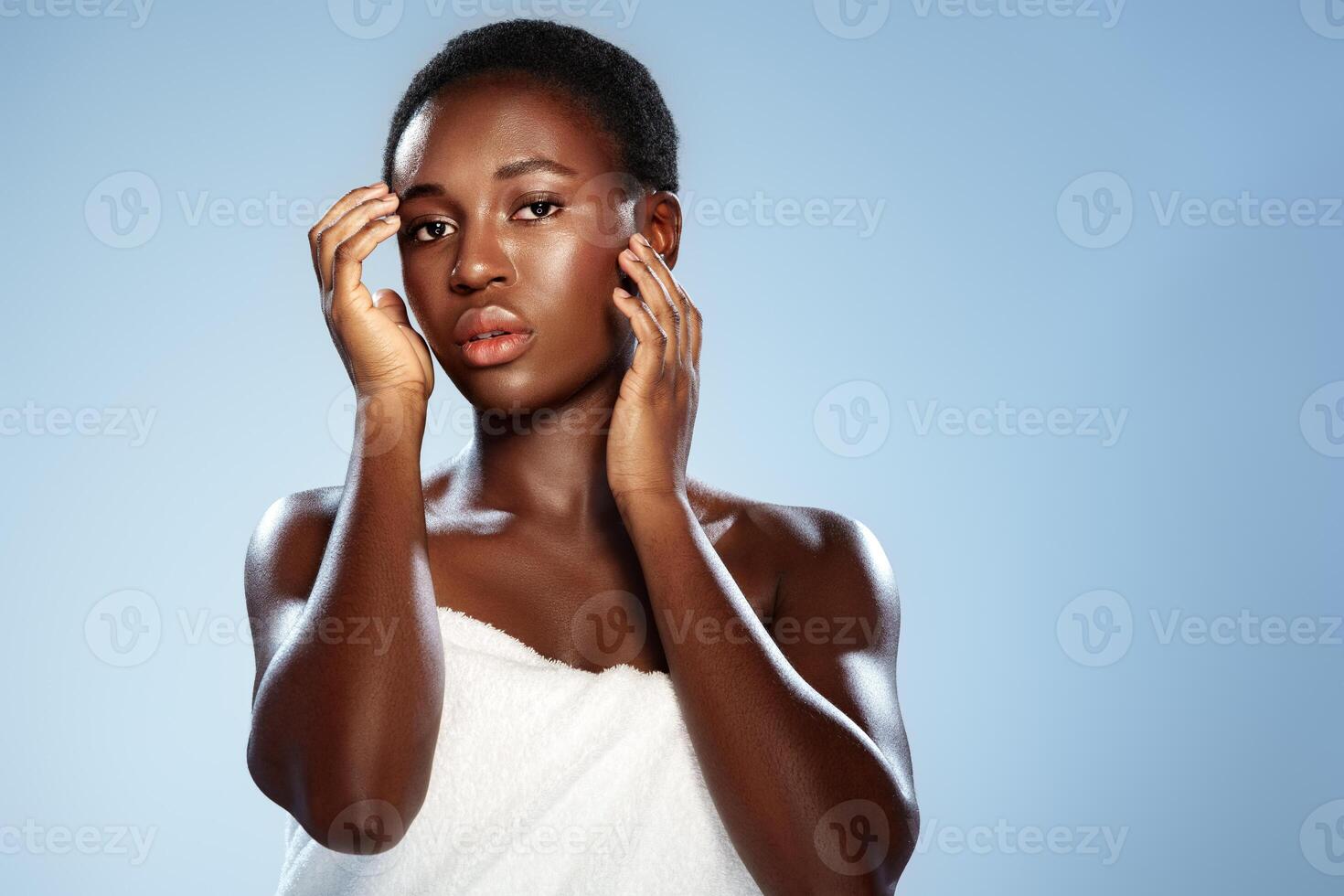 Portrait of a person with short hair posing against a light blue background, expressing emotion and confidence through body language photo