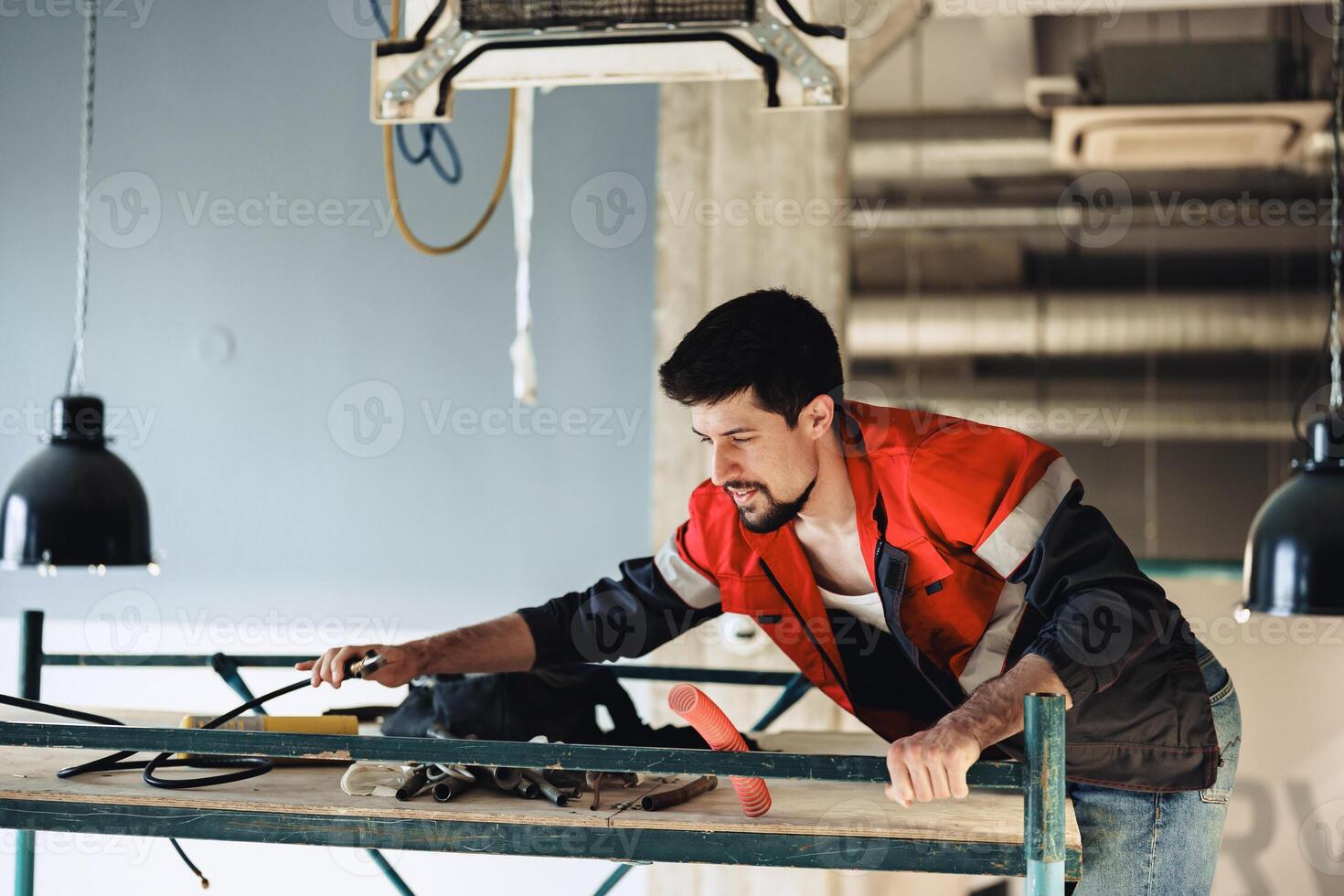 Construction worker performing tasks at a building site while adjusting equipment on scaffolding photo