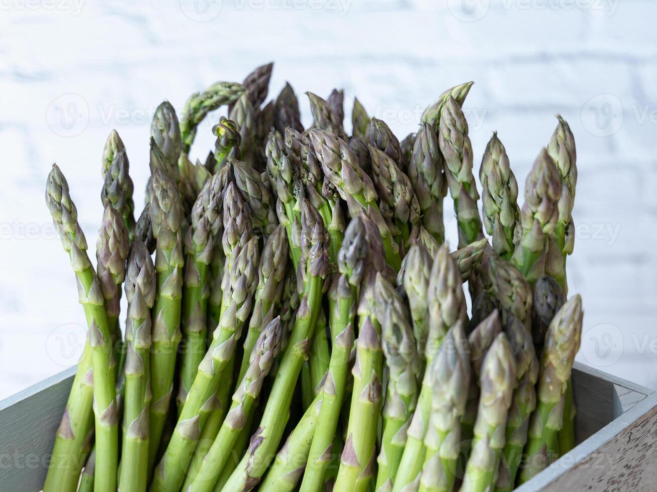 Close up of green asparagus neatly arranged in a weathered gray crate, ideal for market or farm visuals photo