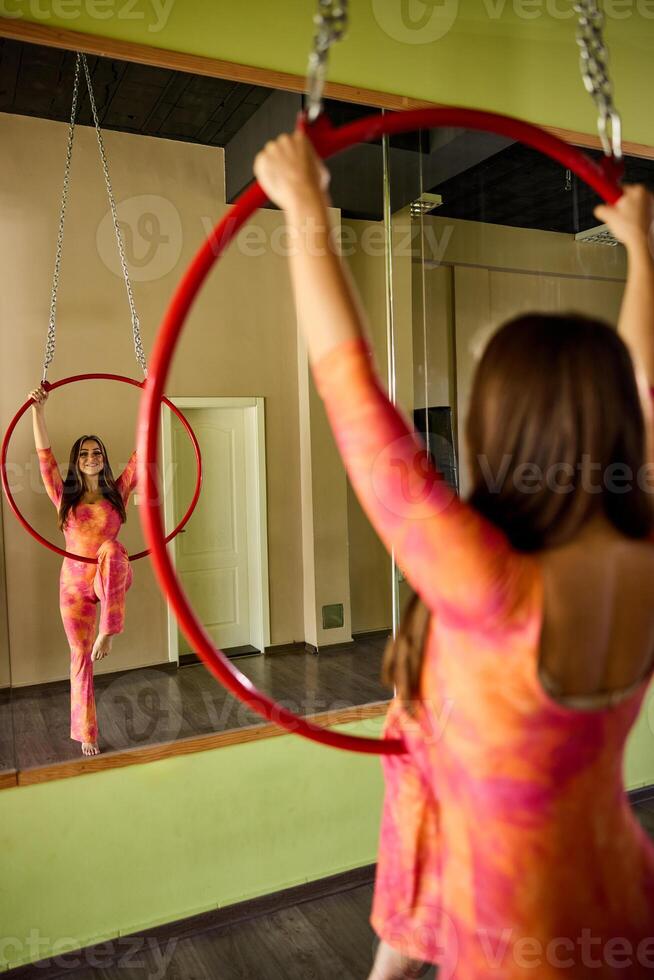 Woman Doing Acrobatics On Aerial Hoop in front of mirror. photo