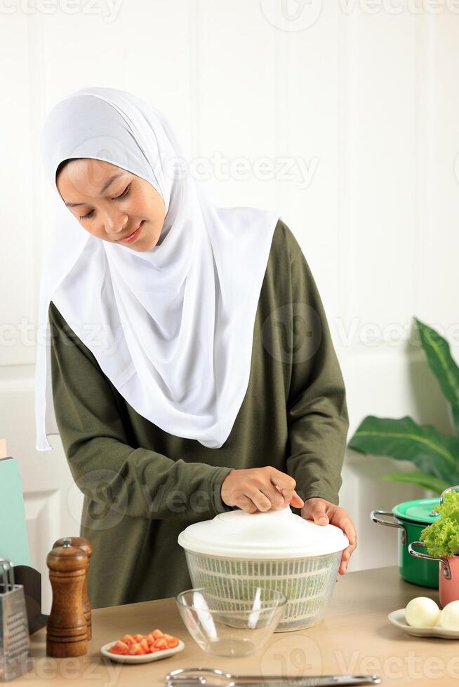 Woman in Hijab Drains Lettuce from the Water in a Salad Spinner photo
