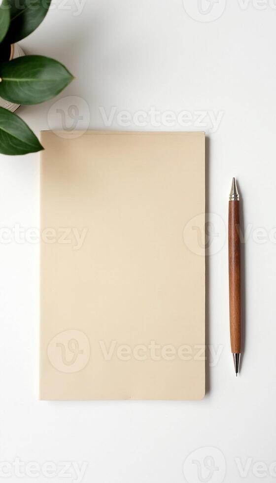 Kraft paper notebook and pen on white surface with natural leaf frame. photo