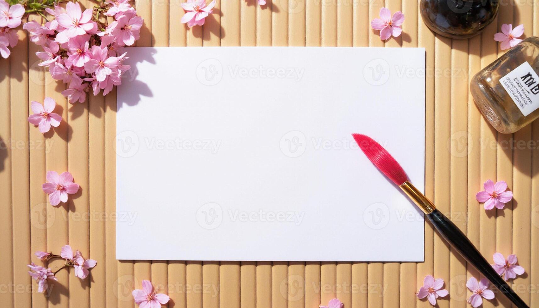 A blank sheet of paper, a paint brush and a bottle of ink on a wooden background photo