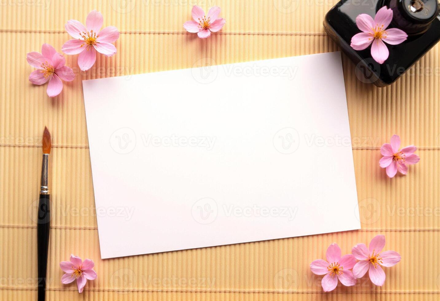 A blank sheet of paper, a pen and a paintbrush on a bamboo mat photo