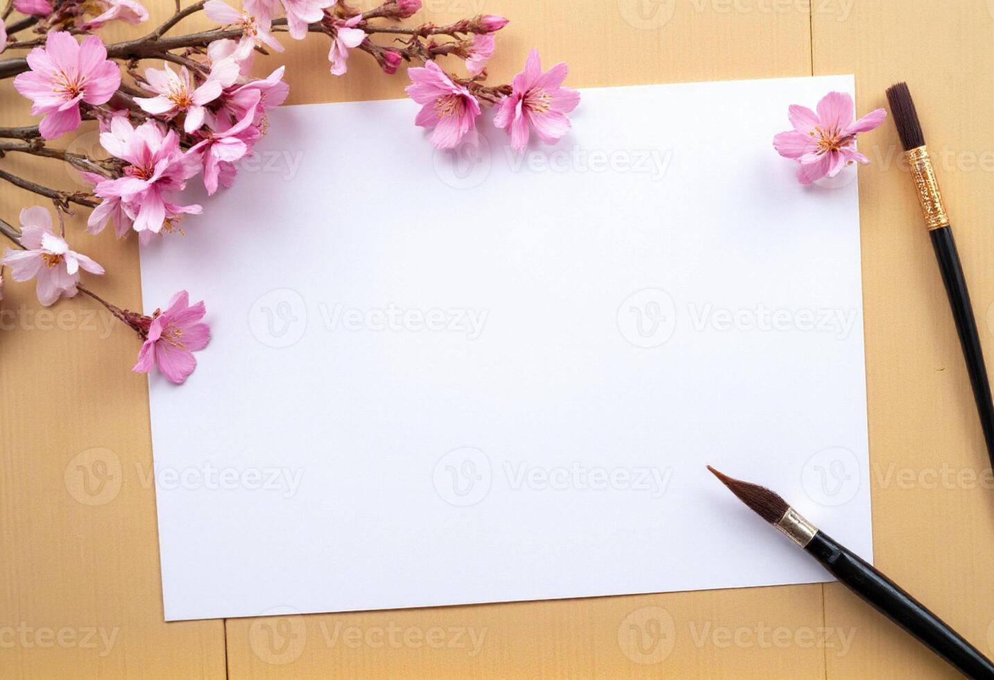 A blank sheet of paper, a paint brush and a cherry blossom branch on a wooden table photo