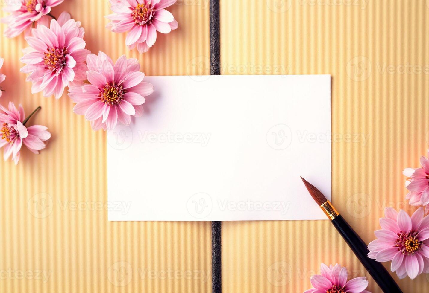 Pink flowers on a yellow background with a blank note card and a pen photo