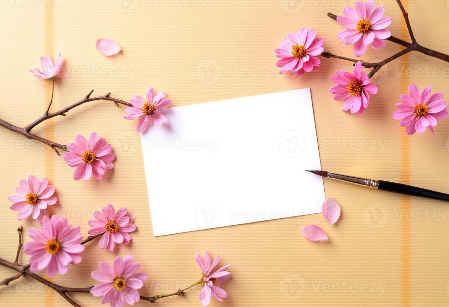 Pink flowers and paper on yellow background with blank space for text photo