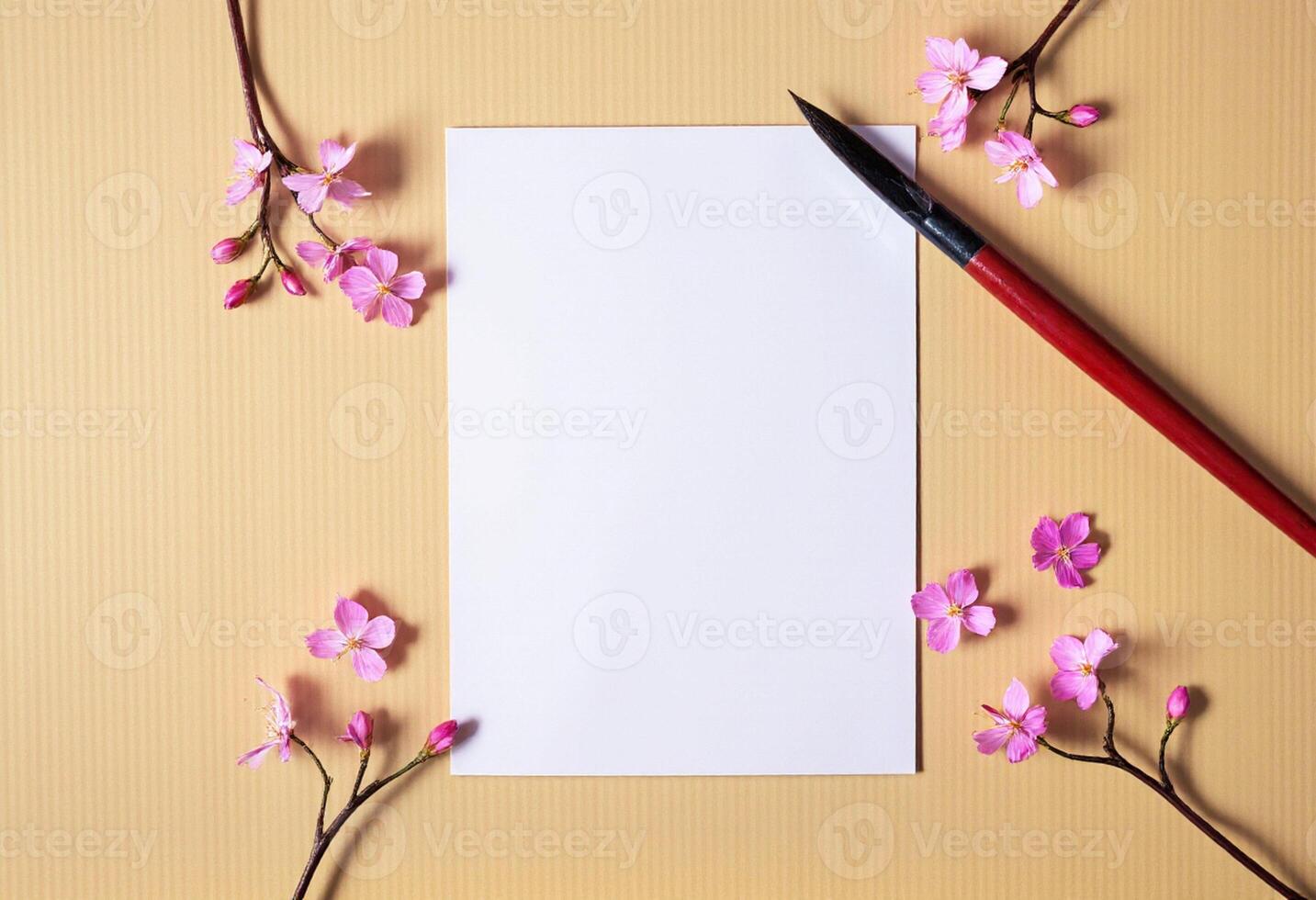 A blank sheet of paper with a red pen and pink flowers on a wooden background photo