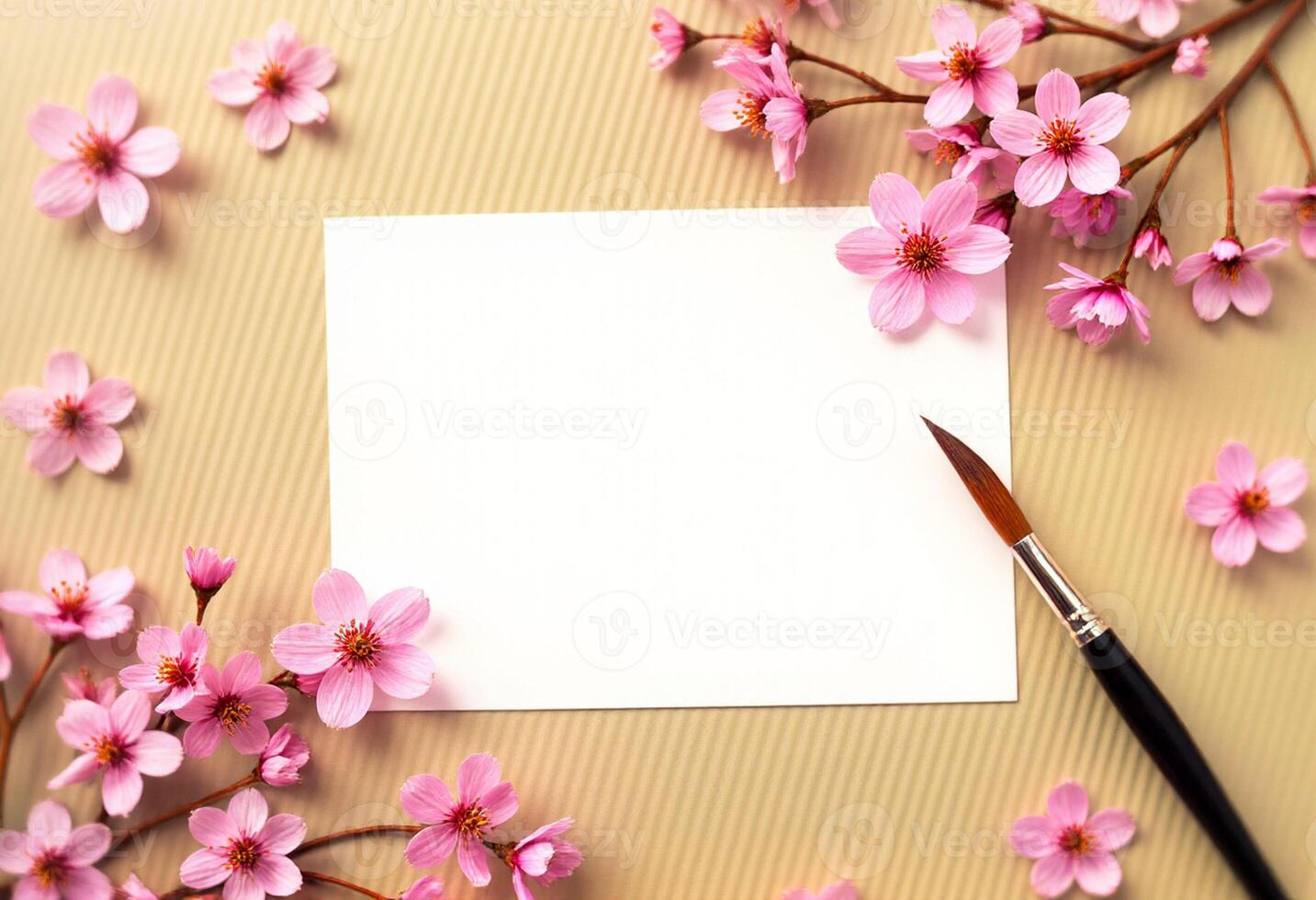 A blank paper with a brush and pink cherry blossom on a beige background photo