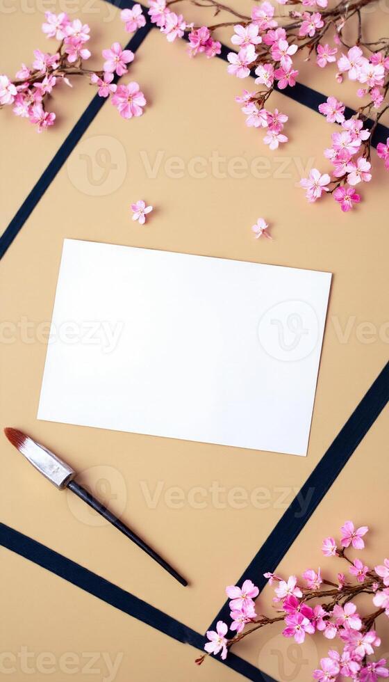 A blank card and paintbrush on a table with pink flowers photo