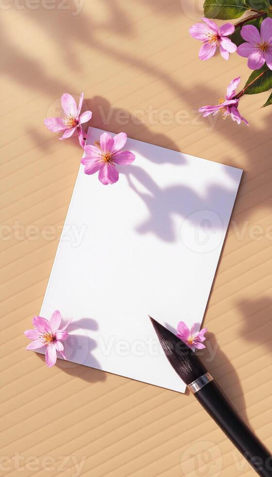 A blank sheet of paper with flowers and a brush on a wooden table photo