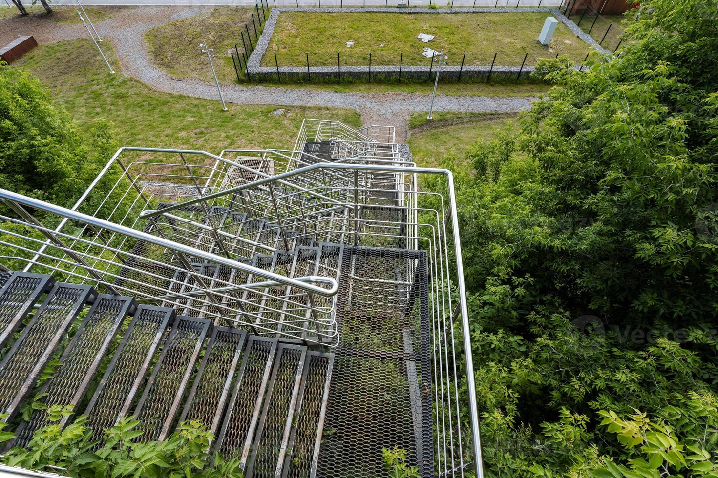 This image captures an aerial view showcasing a fire escape that is beautifully surrounded by a lush landscape of trees and green grass, creating a striking visual contrast photo