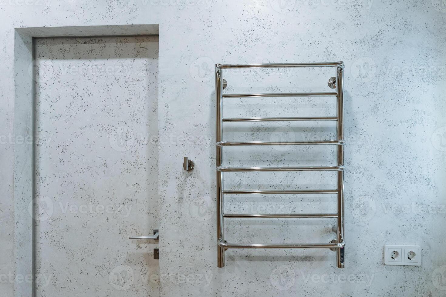 A towel rack is securely hanging on the wall right next to an entrance door, providing easy access for towels in a convenient location for individuals entering or exiting the room photo