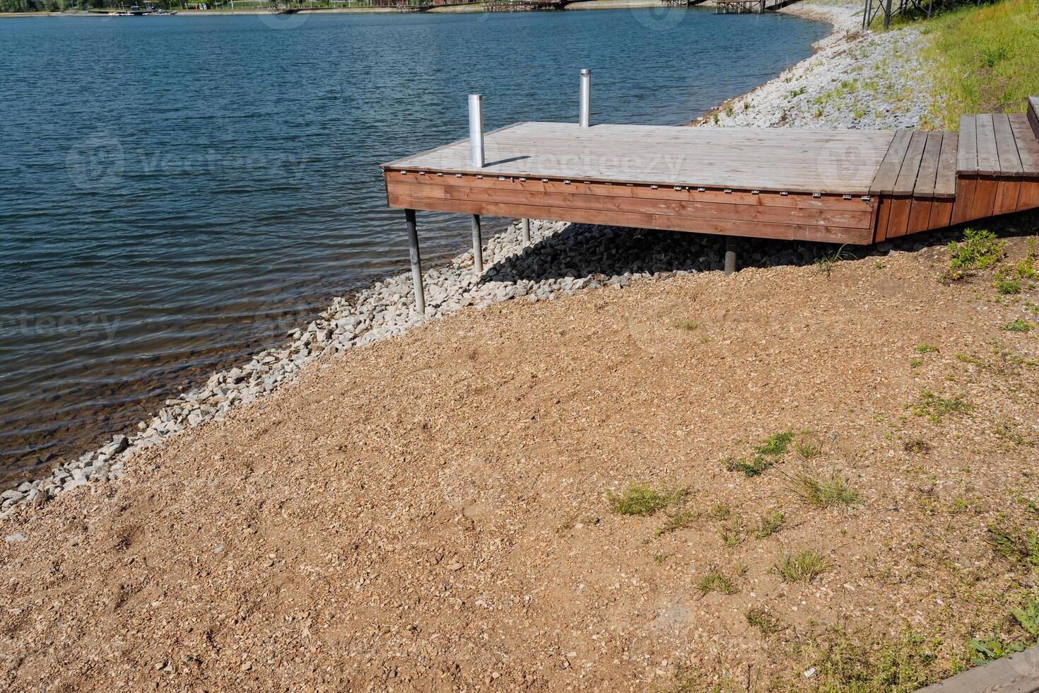 A beautiful wooden dock is perfectly located on the calm shore of a peaceful lake, offering a great place for relaxation and enjoying the tranquility of the water, surrounded by nature photo