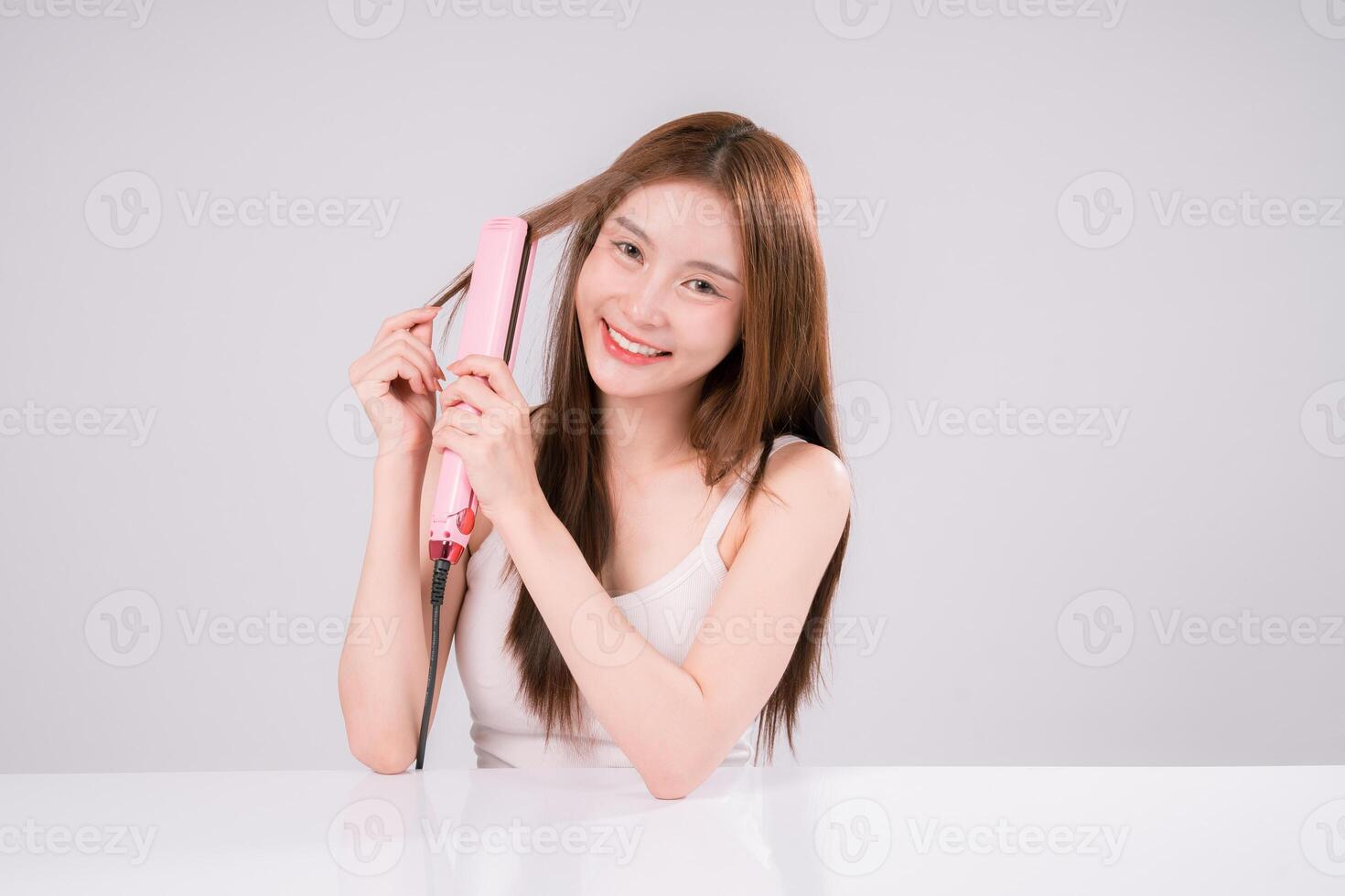 Woman Salon Hairstyle using Iron Hair, straightening Hair with Electric Flat Iron On White photo