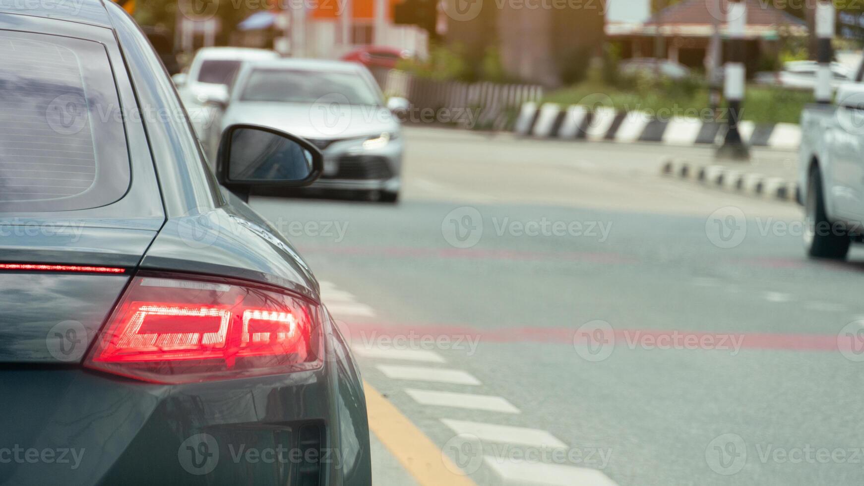 Luxury of dark car with long glowing brake lights. Drive on a road with clear traffic conditions. There are other cars driving on the road. On roads with various traffic control lines. photo