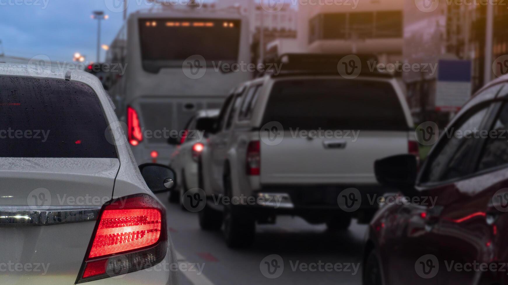 Abstact traffic jam with several vehicles lined up on a road. Close up car with its tail lights illuminated. Traffic congestion during rush hour with environment of rainy time at eveing. photo