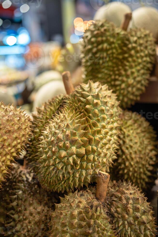 Durian fruits on supermarket shelf ready for customer selection, close up. Grocery stalls in Asia photo