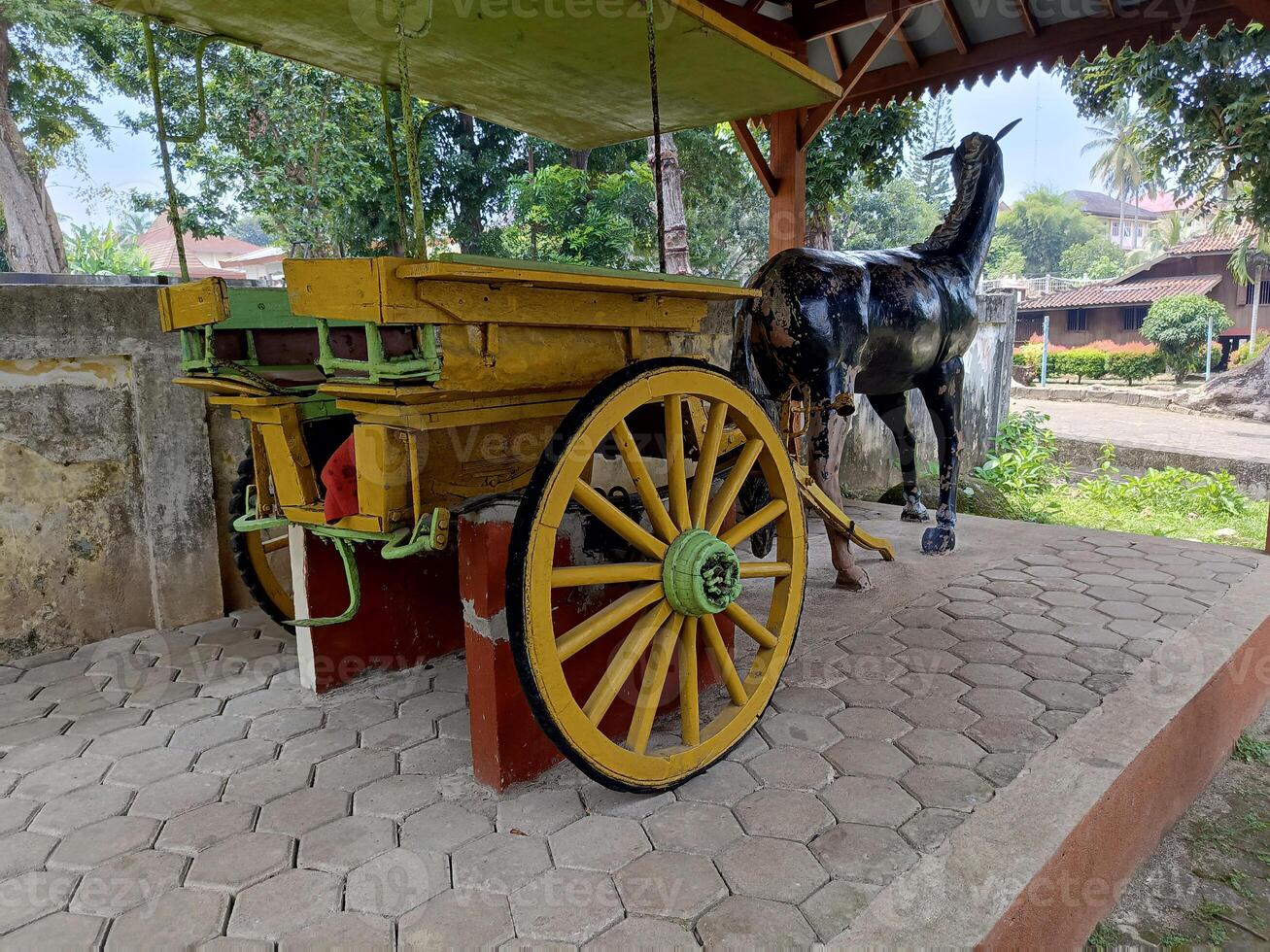 Yellow Horse Cart and Black Stallion Sculpture in Covered Outdoo photo