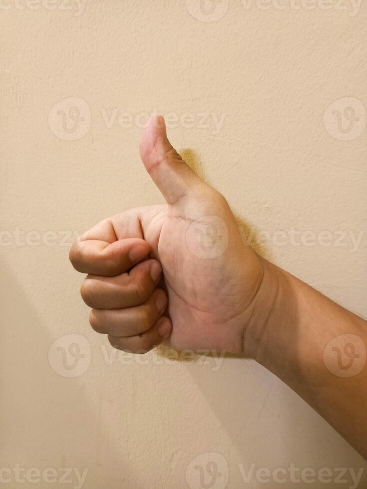 Hand Showing Thumbs Up on Neutral Wall - Approval Concept photo