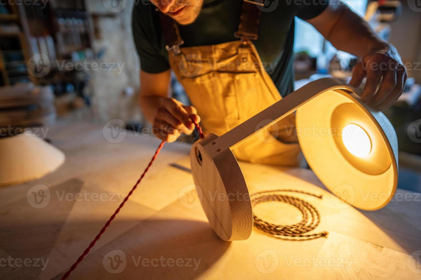 Artisan crafting custom lamp from blueprints. Maker selecting wires, refine design, check connection photo