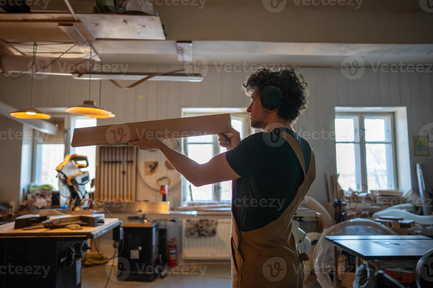 Craftsman checking wooden plank carefully before crafting in carpentry studio, focused manual work photo