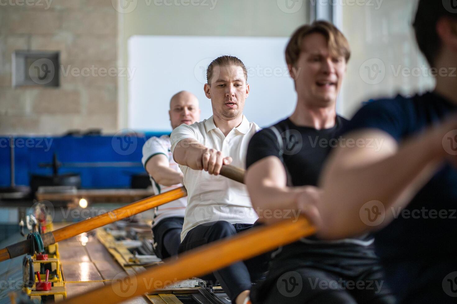 Concentrated tired active rowing team trains paddling on simulator in sports pool, crew preparation photo