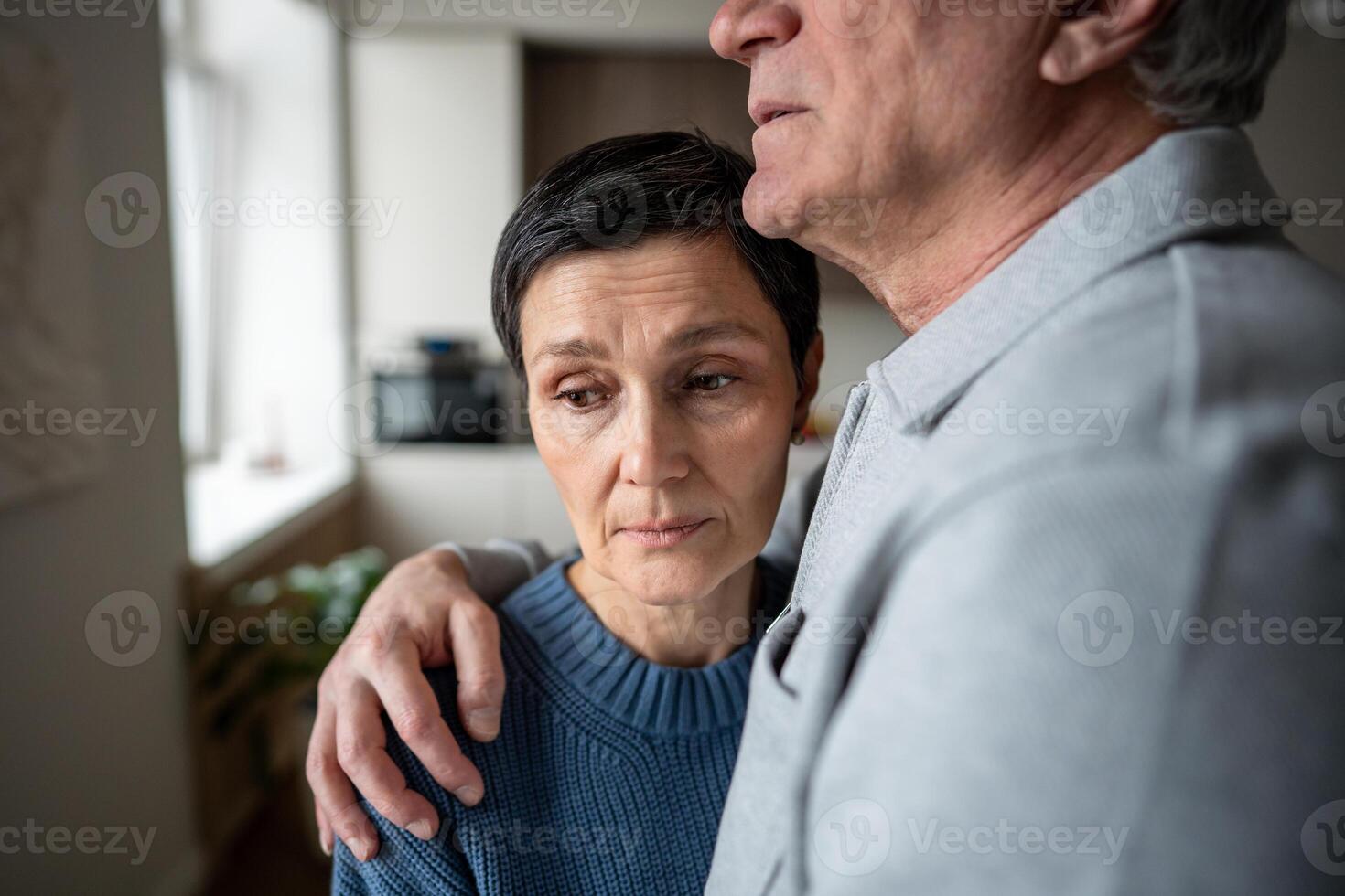 Elderly woman embraced by husband receiving comfort. Senior couple support, marital care aging love photo