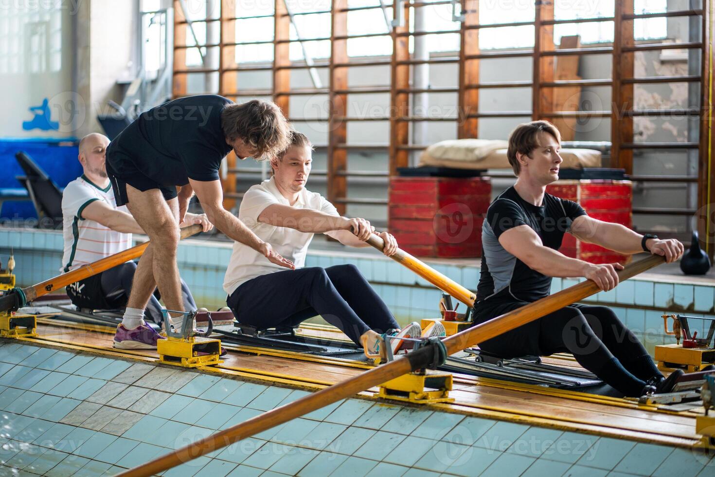 Attentive experienced coach instructs rower crew, correcting posture ensuring synchronized strokes photo