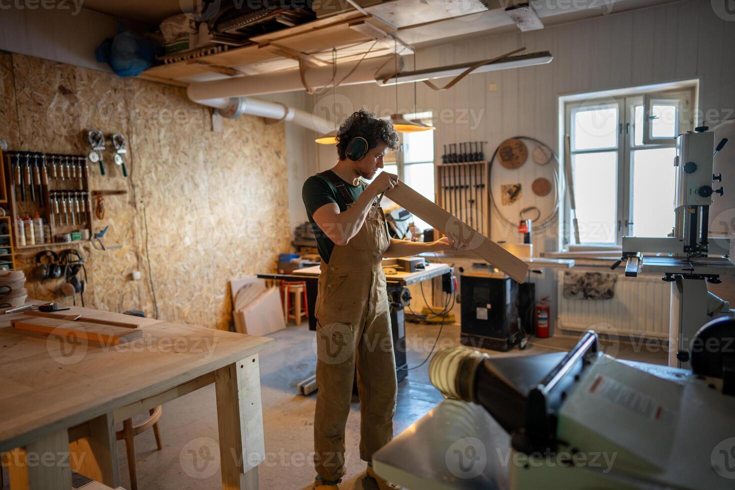 Professional meticulous carpenter inspecting wooden beam quality before workshop processing photo
