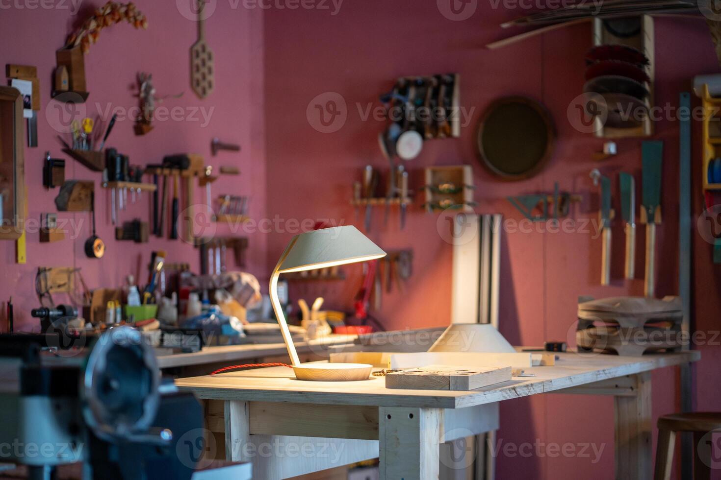 Woodworking studio featuring handmade lamp on worktable. Custom built light item made from plywood photo