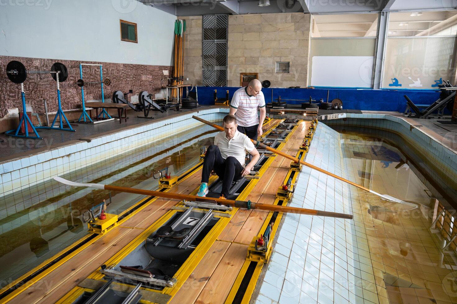 Group of swimmer athletes position properly for rowing simulator training in gym pool, aquatic sport photo