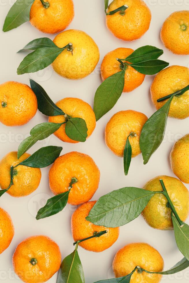 Top view juicy orange yellow tangerines with green leaf, Natural citrus fruit pattern minimal style, light beige background. Organic, healthy, vegetarian and plant-based food concept, pastel tones photo