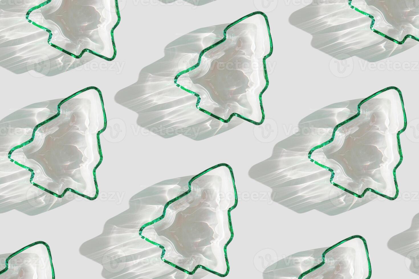 Minimal pattern Green color glass form as New Year trees, Christmas fir at sunlight with beautiful shadows and sparkling sun glare on white background. Winter holiday concept, aesthetic trends photo
