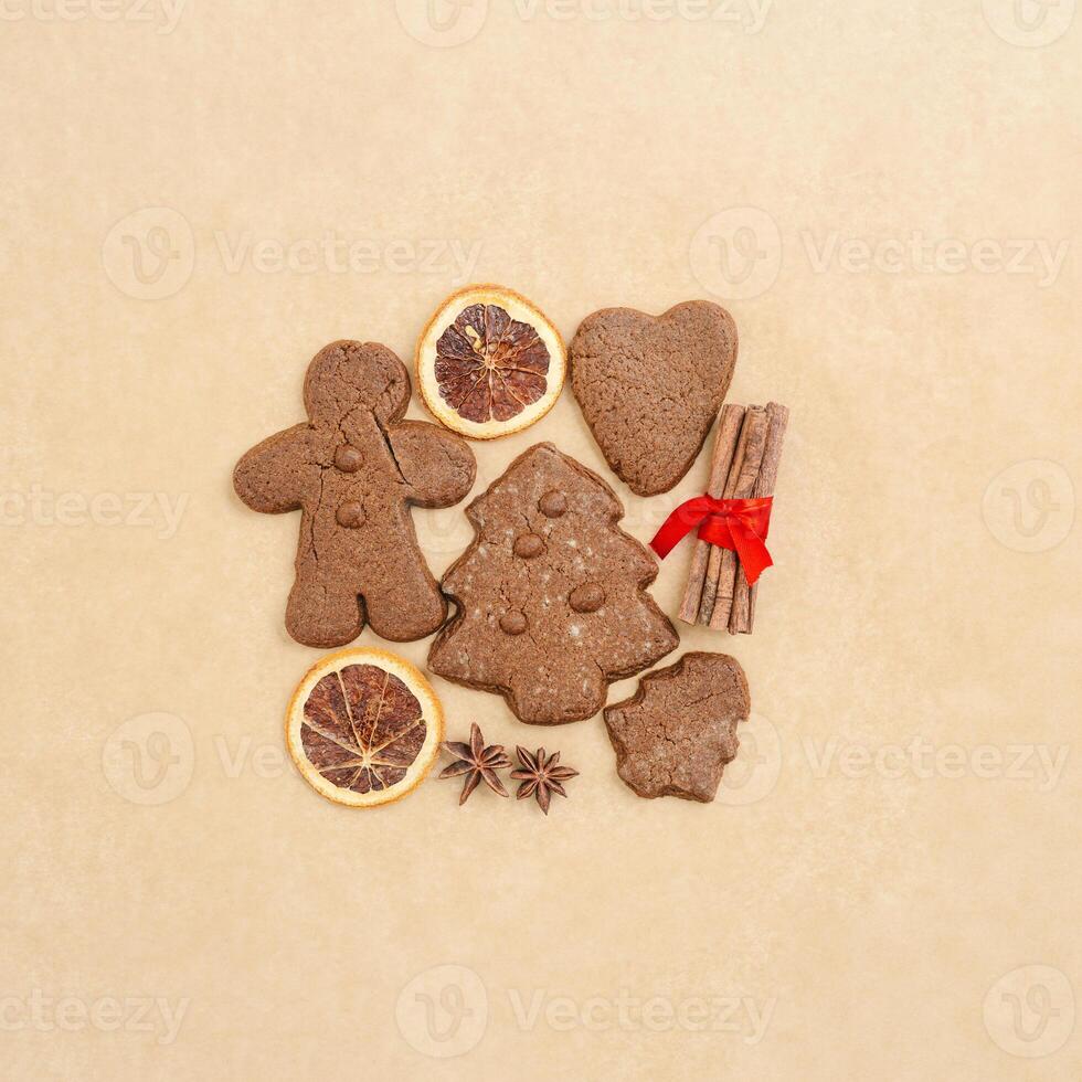 Christmas gingerbread cookies, biscuits, dry oranges sliced, cinnamon sticks on beige baking paper. Top view brown trend pattern, flat lay holiday sweet food, traditional bakery, new year photo