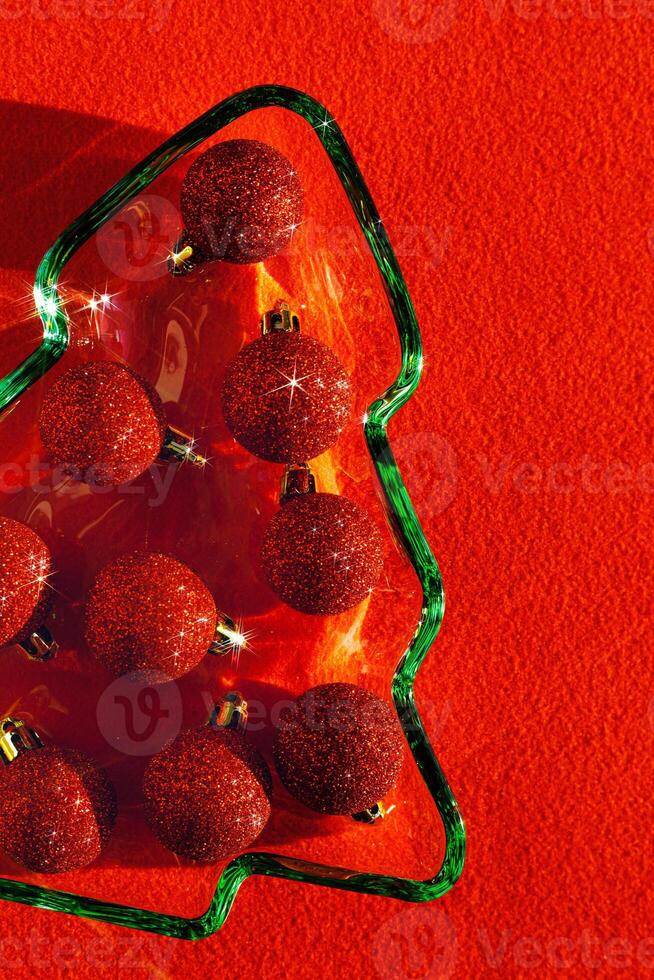 Plate as New Year tree with shining red Christmas balls on red textile, Christmas tree from green glowing glass glare. Sunlight and shadow, sparkling holiday food, xmas trendy still life photo